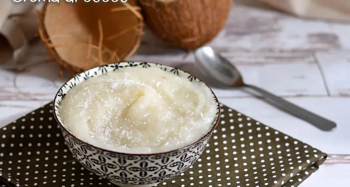 Una ciotola di deliziosa crema al cocco, cosparsa di cocco grattugiato, accanto a gusci di cocco e un cucchiaio.