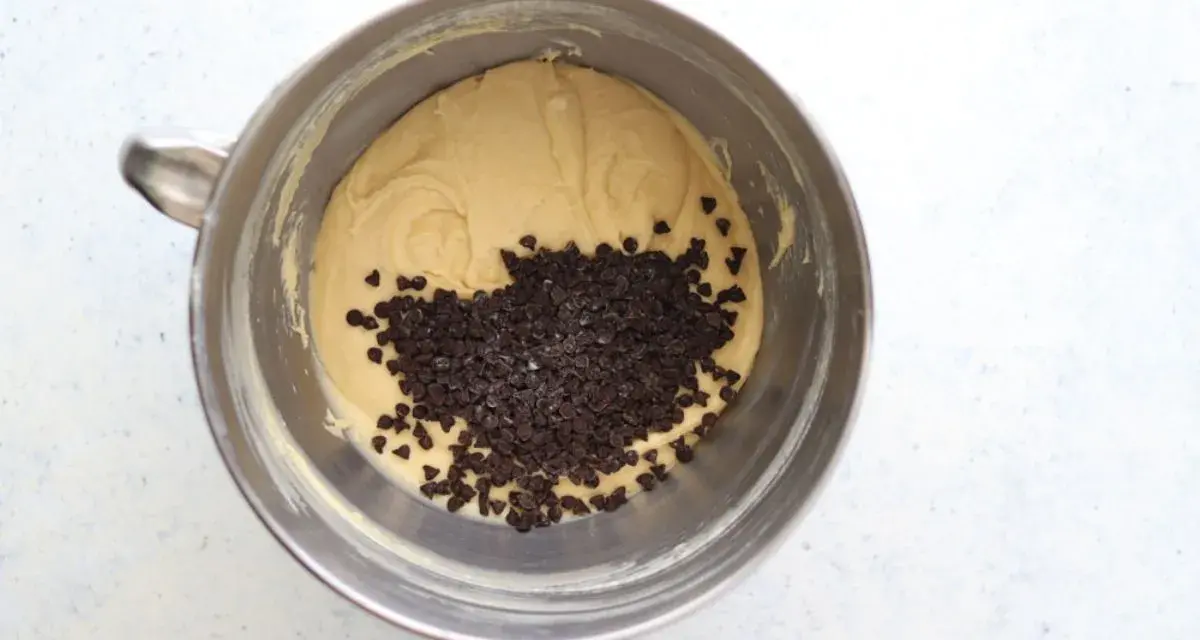 Impasto per torta con abbondanti gocce di cioccolato in una ciotola di metallo, pronto per essere infornato.