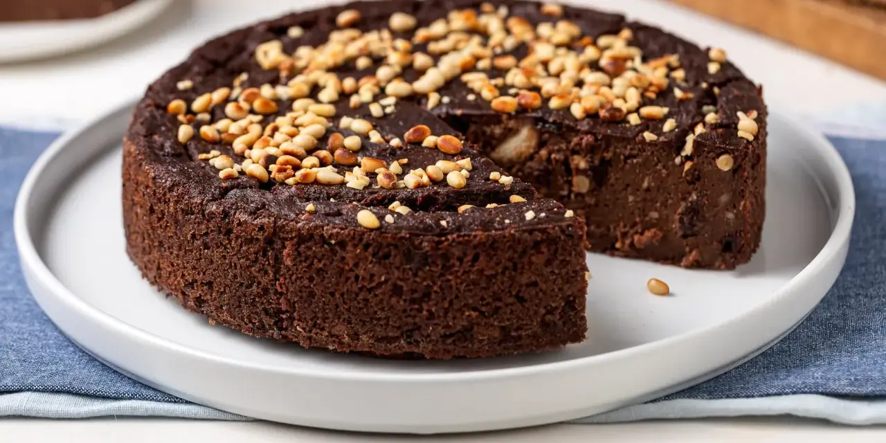 Torta paesana al cioccolato, ricca e umida, guarnita con pinoli tostati. Un dolce rustico che sa di casa.