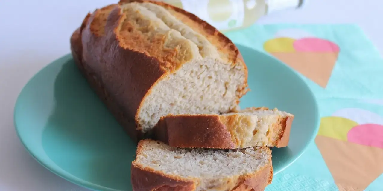 Fetta di banana bread light su piatto turchese, con bottiglia e tovaglioli a tema gelato sullo sfondo.