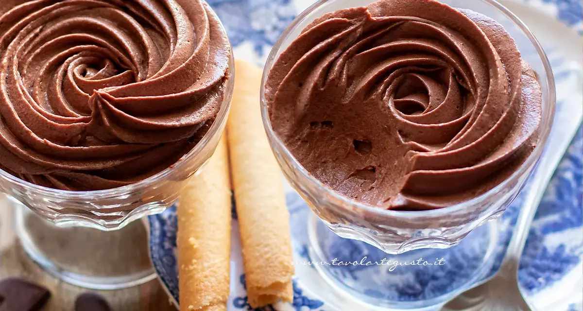 Deliziosa mousse al cioccolato in coppette di vetro, accompagnata da biscotti arrotolati e cuoricini di cioccolato.