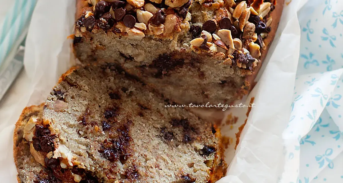 Fetta di banana bread con gocce di cioccolato e noci, guarnita con mandorle e nocciole tritate.