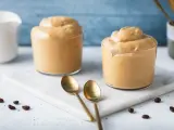 Due bicchieri di soffice crema di caffè, perfetta ricetta crema di caffè senza panna e senza caffè solubile. Due cucchiaini dorati e chicchi di caffè completano la scena.