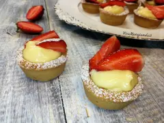 Deliziosi cestini alla frutta con crema pasticcera e fragole fresche, spolverati di zucchero a velo.