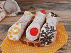 Cannoli siciliani decorati con canditi, ciliegie e gocce di cioccolato, pronti per essere gustati. Ingredienti cannolo siciliano perfetti.