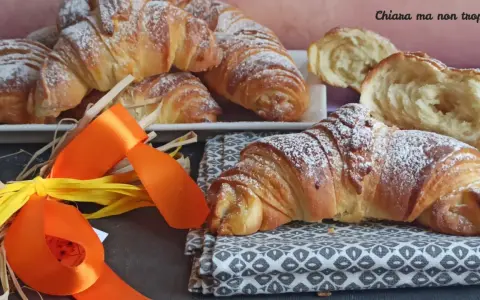 Croissant dorati e soffici, dolci lievitati spolverati di zucchero a velo, pronti per una colazione speciale.
