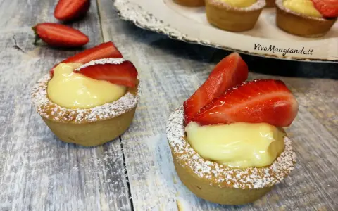 Deliziosi cestini alla frutta con crema pasticcera e fragole fresche, spolverati di zucchero a velo.