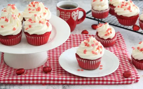 Deliziosi muffin red velvet con glassa bianca e cuoricini rossi, perfetti per San Valentino.