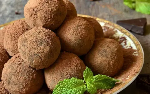 Pile di tartufi al cioccolato facili e veloci, spolverati di cacao, con menta fresca e un pezzetto di cioccolato fondente.