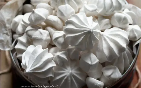 Un cesto pieno di meringhe soffici, perfette per la tua ricetta. Dolci e leggere, un piacere da gustare.