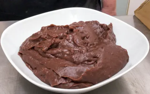 Crema pasticcera al cioccolato, densa e lucida, in una ciotola bianca.