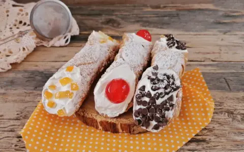 Cannoli siciliani decorati con canditi, ciliegie e gocce di cioccolato, pronti per essere gustati. Ingredienti cannolo siciliano perfetti.