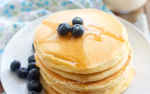 Pancakes soffici con albumi, guarniti con mirtilli freschi e sciroppo d'acero. Un dolce inizio di giornata.
