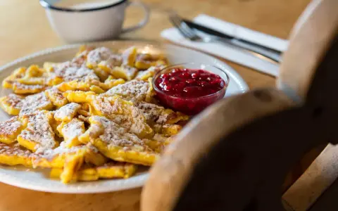 Frittata dolce tirolese cosparsa di zucchero a velo, servita con marmellata di mirtilli rossi.