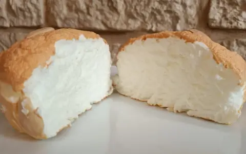 Una fetta di torta nuvola, soffice e leggera, con una crosticina dorata e un interno bianco e arioso.