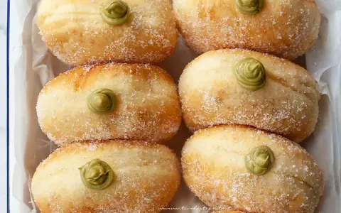 Sei bomboloni soffici, cosparsi di zucchero e guarniti con una deliziosa crema al pistacchio.