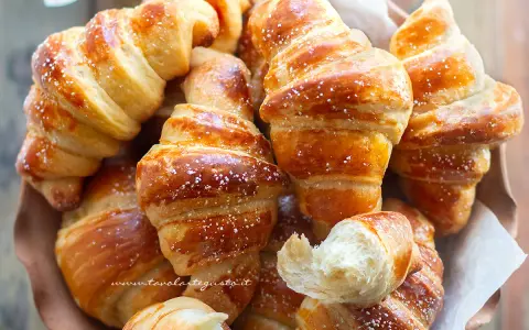 Brioches fatte in casa, dorate e soffici, cosparse di zucchero a velo. Un profumo invitante che ricorda la colazione perfetta.