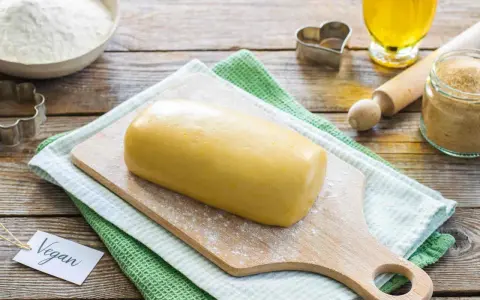 Impasto giallo pronto per biscotti, con un'etichetta "Vegan" e ingredienti come farina, zucchero e olio.