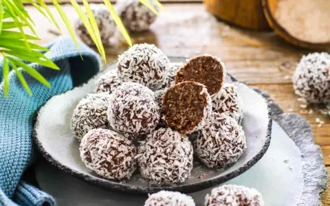 Praline al cioccolato facili e veloci, ricoperte di cocco grattugiato. Un morso rivela un interno morbido e goloso.