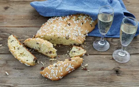 Fette di ciambella romagnola, cosparse di zuccherini, accanto a due bicchieri di spumante.