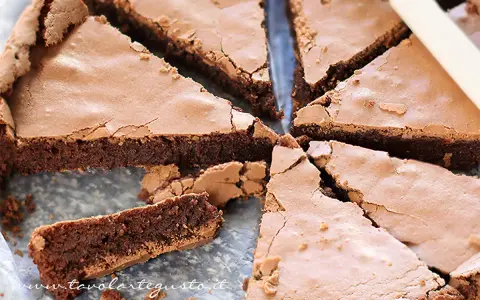 Torta tenerina con cuore morbido, tagliata a fette triangolari. La superficie è leggermente screpolata, rivelando la consistenza umida e golosa.