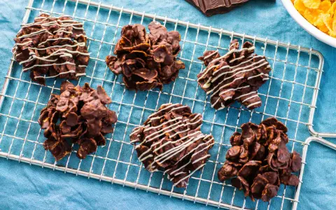 Dolcetti croccanti al cioccolato, simili a rose del deserto ricetta, su una griglia di raffreddamento. Alcuni sono decorati con cioccolato bianco.