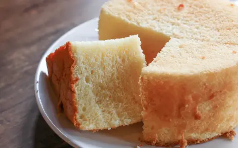 Il segreto per torte alte e soffici: una fetta di torta soffice e dorata su un piatto bianco, pronta per essere gustata.