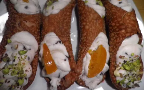 Cannoli siciliani con ripieno cremoso, gocce di cioccolato e pistacchi. Una ricetta semplice per un dolce irresistibile.