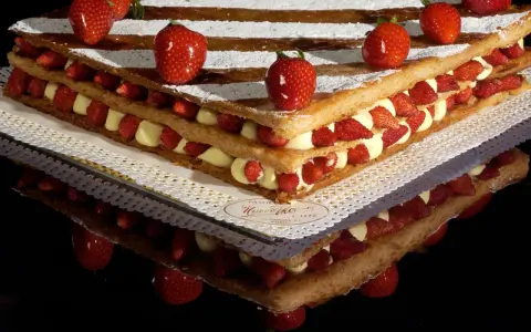 Un invitante millefoglie cake con strati di crema pasticcera e fragole fresche, decorato con fragole intere e zucchero a velo.