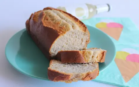 Fetta di banana bread light su piatto turchese, con bottiglia e tovaglioli a tema gelato sullo sfondo.