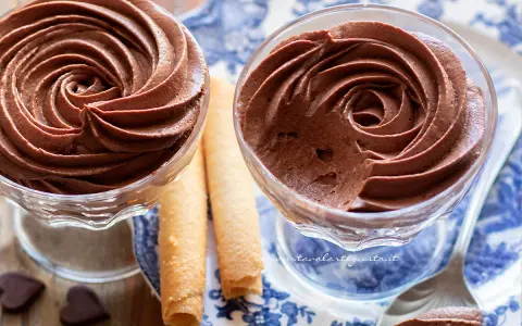 Deliziosa mousse al cioccolato in coppette di vetro, accompagnata da biscotti arrotolati e cuoricini di cioccolato.