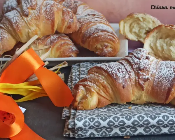 Croissant dorati e soffici, dolci lievitati spolverati di zucchero a velo, pronti per una colazione speciale.