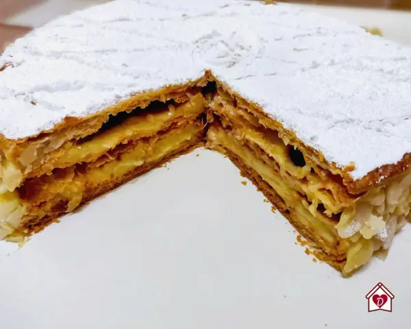 Un delizioso millefoglie alla crema, con strati croccanti di pasta sfoglia e una ricca crema pasticcera, spolverato di zucchero a velo e mandorle.