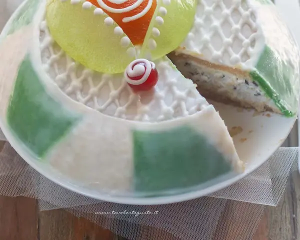 Una fetta di cassata siciliana palermitana, con decorazioni in glassa bianca e canditi colorati, mostra il suo ripieno cremoso.