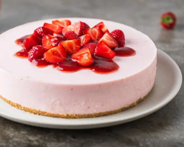 Deliziosa torta fragole e mascarpone senza cottura, guarnita con fragole fresche e salsa rossa.