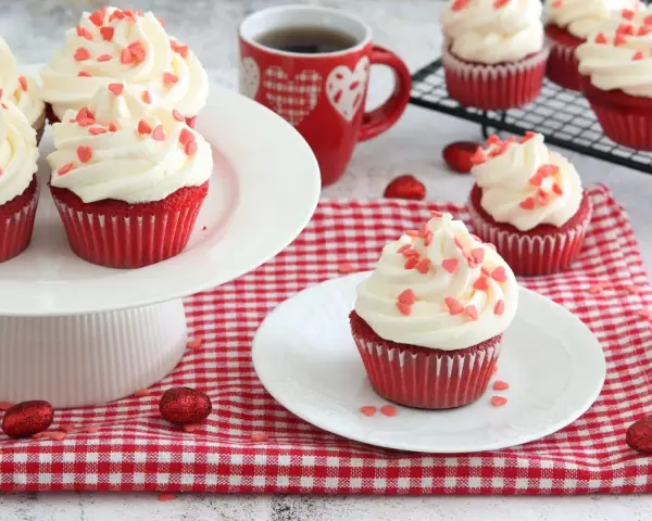 Deliziosi muffin red velvet con glassa bianca e cuoricini rossi, perfetti per San Valentino.