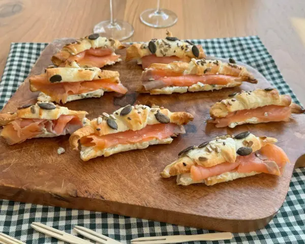 Cornetti di pasta sfoglia ripieni di salmone affumicato e formaggio cremoso, guarniti con semi.