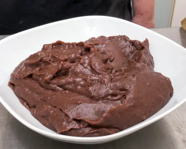 Crema pasticcera al cioccolato, densa e lucida, in una ciotola bianca.