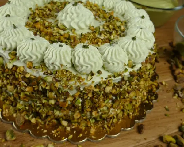 Delizioso dolce con crema al pistacchio già pronta, ricoperto di granella di pistacchi e decorato con ciuffi di crema.
