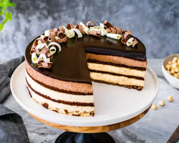 Una magnifica torta sette veli, con strati di mousse al cioccolato e crema, ricoperta da glassa lucida e riccioli di cioccolato.