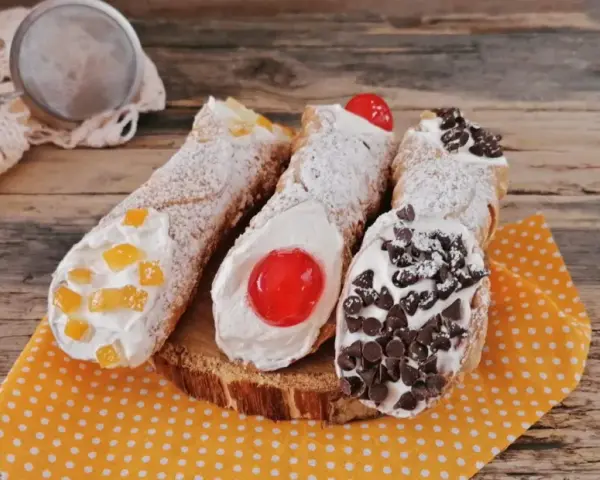 Cannoli siciliani decorati con canditi, ciliegie e gocce di cioccolato, pronti per essere gustati. Ingredienti cannolo siciliano perfetti.