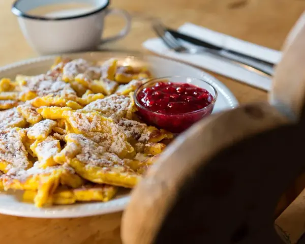 Frittata dolce tirolese cosparsa di zucchero a velo, servita con marmellata di mirtilli rossi.