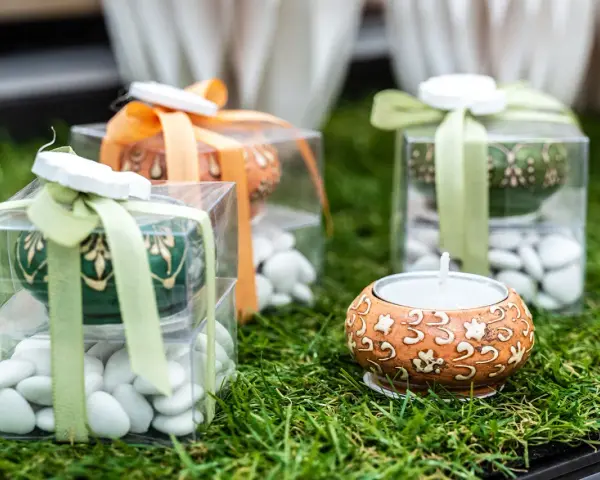 Confezioni regalo con confetti bianchi, candela e decorazioni floreali. Il significato dei confetti, augurio di dolcezza e prosperità.