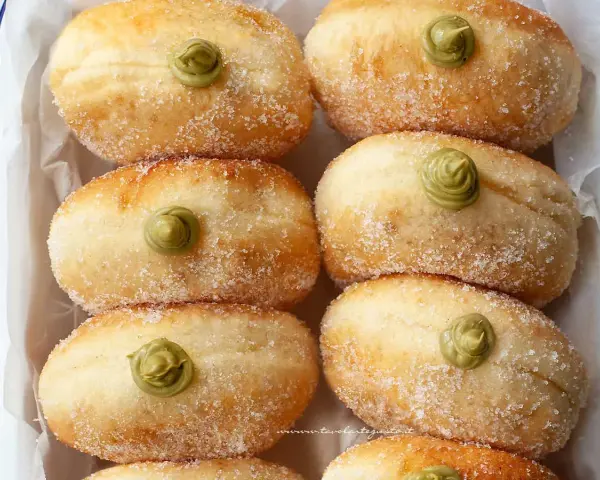 Sei bomboloni soffici, cosparsi di zucchero e guarniti con una deliziosa crema al pistacchio.