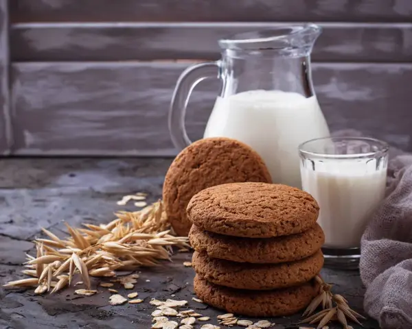 Biscotti farina di avena friabilissimi, perfetti con un bicchiere di latte fresco. Un'immagine che evoca colazioni genuine e momenti di puro piacere.