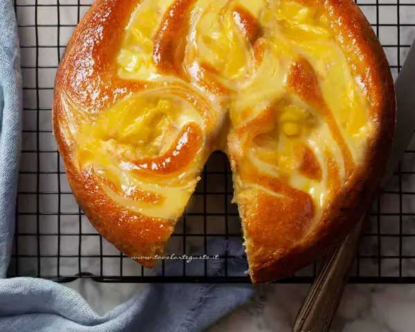 Torta soffice con un vortice di crema pasticcera dorata, appena sfornata e pronta per essere gustata.