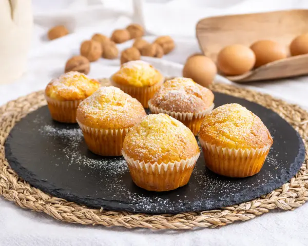 Sei muffin allo yogurt spolverati di zucchero a velo, pronti per essere gustati.