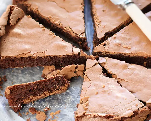 Torta tenerina con cuore morbido, tagliata a fette triangolari. La superficie è leggermente screpolata, rivelando la consistenza umida e golosa.