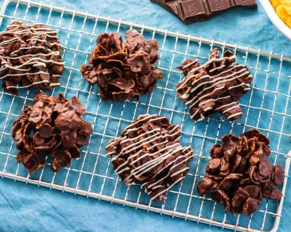 Dolcetti croccanti al cioccolato, simili a rose del deserto ricetta, su una griglia di raffreddamento. Alcuni sono decorati con cioccolato bianco.