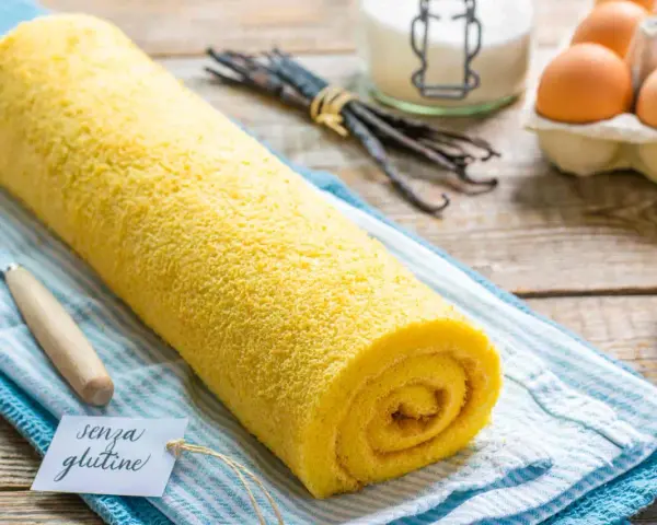 Rotolo giallo soffice, un delizioso pasta biscotto senza glutine, pronto per essere gustato. Ingredienti freschi sullo sfondo.